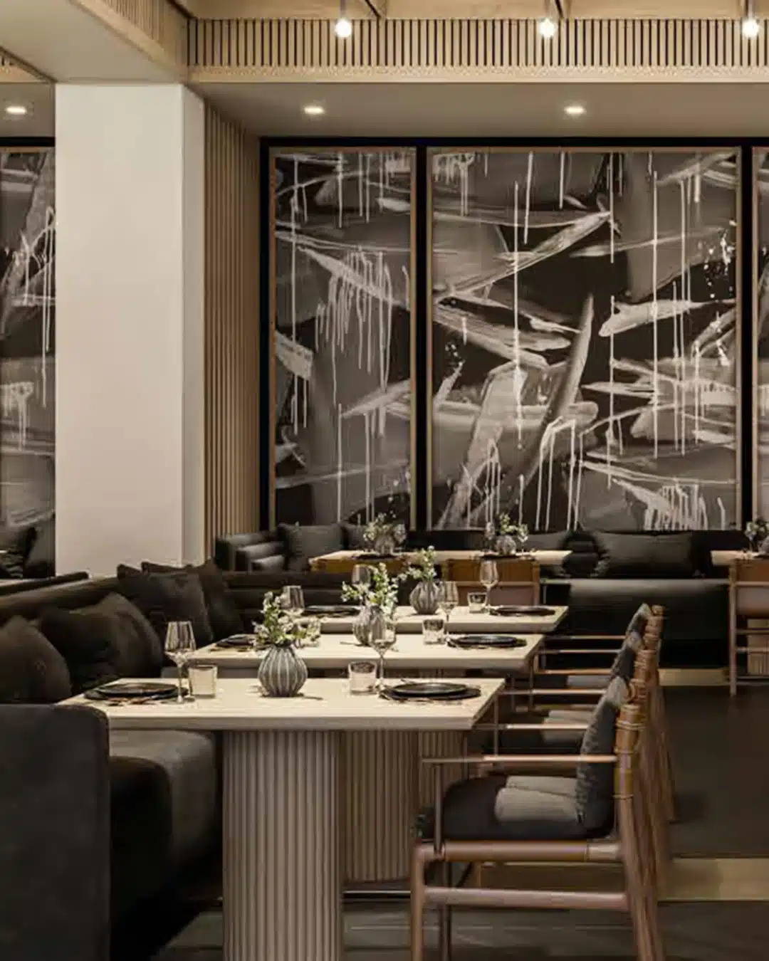 Upscale dining area with white tables set for service, gray booths, and abstract black-and-white wall panels behind.